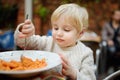 Cute toddler boy eating pasta in Italian indoors restaurant Royalty Free Stock Photo