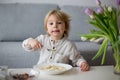 Cute toddler boy, eating pasta with white cheese at home Royalty Free Stock Photo