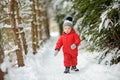 Cute toddler boy having fun on a walk in snow covered pine forest on chilly winter day. Child exploring nature. Winter activities Royalty Free Stock Photo