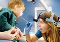 A cute toddler boy with his mother are at an appointment with a pediatric ENT. The doctor otolaryngologist is examines the throat Royalty Free Stock Photo