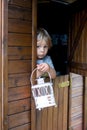 Cute toddler boy, holding lantern, hiding behind wooden door in little playhouse Royalty Free Stock Photo