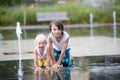 Cute toddler boy and older brothers, playing on a jet fountains with water splashing around Royalty Free Stock Photo