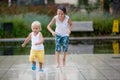 Cute toddler boy and older brothers, playing on a jet fountains with water splashing around Royalty Free Stock Photo