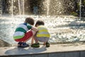 Cute toddler boy and older brothers, playing on a jet fountains with water splashing around, summertime Royalty Free Stock Photo