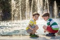 Cute toddler boy and older brothers, playing on a jet fountains with water splashing around, summertime Royalty Free Stock Photo