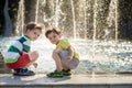 Cute toddler boy and older brothers, playing on a jet fountains with water splashing around, summertime Royalty Free Stock Photo