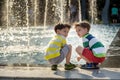 Cute toddler boy and older brothers, playing on a jet fountains with water splashing around, summertime Royalty Free Stock Photo