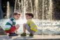 Cute toddler boy and older brothers, playing on a jet fountains with water splashing around, summertime Royalty Free Stock Photo