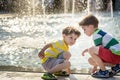 Cute toddler boy and older brothers, playing on a jet fountains with water splashing around, summertime Royalty Free Stock Photo