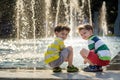 Cute toddler boy and older brothers, playing on a jet fountains with water splashing around, summertime Royalty Free Stock Photo