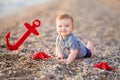 Cute toddler boy playing on the beach with sea red star and anchor Royalty Free Stock Photo