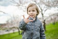 Cute toddler boy playing in blooming cherry tree garden on beautiful spring day. Adorable baby having fun outdoors Royalty Free Stock Photo