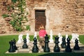 Cute toddler boy playing giant chess outside