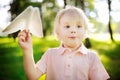 Cute toddler boy playing with paper plane in a summer park Royalty Free Stock Photo