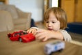 Cute toddler boy playing with red toy car. Small child having fun with toys. Kid spending time in a cozy living room at home Royalty Free Stock Photo