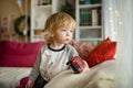 Cute toddler boy playing with red toy car. Small child having fun with toys. Kid spending time in a cozy living room at home Royalty Free Stock Photo