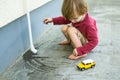 Cute toddler boy playing with yellow toy car outdoors. Kid exploring nature. Small child having fun with toys Royalty Free Stock Photo