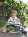 Cute toddler boy sits in front of a large stack of children`s books