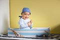 Cute toddler boy, sitting in a big wooden boat at home, playing Royalty Free Stock Photo