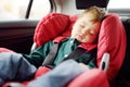 Cute toddler boy sleeping in car seat. Portrait of pretty little child during family road trip. Safety transportation of baby by Royalty Free Stock Photo