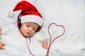 A cute toddler boy is sleeping in a santa hat and red headphones and near the wiring in the form of the heart Royalty Free Stock Photo