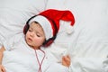 A cute toddler boy is sleeping in a santa hat and red headphones Royalty Free Stock Photo