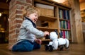 A cute toddler boy standing indoors at home, playing with robotic dog. Royalty Free Stock Photo