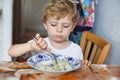 Cute toddler boy of three years eating pasta at home kitchen Royalty Free Stock Photo