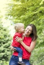 Cute toddler boy whispers in the mother`s ear. Kid kisses mom on the cheek. Very emotional mom and baby. Family look clothing. Co Royalty Free Stock Photo