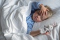 Cute toddler boy sleeping in bed, holding toy bunny in one hand and shielding his eyes from the morning sun with the other. Royalty Free Stock Photo