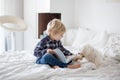 Cute toddler child and puppy dog  lying on the bed  reading book together  family time Royalty Free Stock Photo