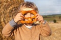 Cute toddler eating German pretzel on goden hay field