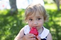 Cute toddler girl with big eyes drinking water from baby bottle outdoors in sunny summer day. Royalty Free Stock Photo