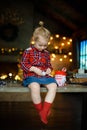 Cute toddler girl eating chocolate egg sitting in a hunting house decorated for Christmas. The concept of a Christmas morning. Royalty Free Stock Photo