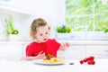 Cute toddler girl eating spaghetti in a white kitchen Royalty Free Stock Photo