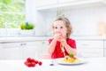 Cute toddler girl eating spaghetti in a white kitchen Royalty Free Stock Photo