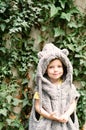 Cute toddler girl in fluffy coat playing near the wall with ivy