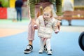 Cute toddler girl having fun on outdoor playground. Young father is teaching his little daughter to walk. First step of baby. Royalty Free Stock Photo