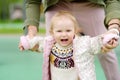 Cute toddler girl having fun on outdoor playground. Young father is teaching his little daughter to walk. First step of baby. Royalty Free Stock Photo