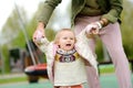 Cute toddler girl having fun on outdoor playground. Young father is teaching his little daughter to walk. First step of baby. Royalty Free Stock Photo