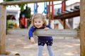 Cute toddler girl having fun on playground. Happy healthy little child climbing, swinging and sliding on different Royalty Free Stock Photo