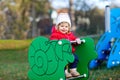 Cute toddler girl having fun on playground. Happy healthy little child climbing, swinging and sliding on different Royalty Free Stock Photo