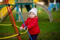 Cute toddler girl having fun on playground. Happy healthy little child climbing, swinging and sliding on different Royalty Free Stock Photo