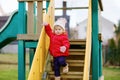 Cute toddler girl having fun on playground. Happy healthy little child climbing, swinging and sliding on different Royalty Free Stock Photo