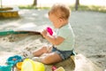 Cute toddler girl playing in sand on outdoor playground. Beautiful baby having fun on sunny warm summer day. Child with colorful Royalty Free Stock Photo