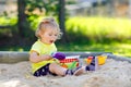 Cute toddler girl playing in sand on outdoor playground. Beautiful baby having fun on sunny warm summer sunny day. Happy Royalty Free Stock Photo