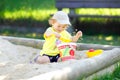 Cute toddler girl playing in sand on outdoor playground. Beautiful baby having fun on sunny warm summer sunny day. Happy Royalty Free Stock Photo