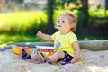 Cute toddler girl playing in sand on outdoor playground. Beautiful baby having fun on sunny warm summer sunny day. Happy Royalty Free Stock Photo