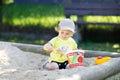 Cute toddler girl playing in sand on outdoor playground. Beautiful baby having fun on sunny warm summer sunny day. Happy Royalty Free Stock Photo