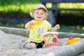 Cute toddler girl playing in sand on outdoor playground. Beautiful baby having fun on sunny warm summer sunny day. Happy Royalty Free Stock Photo